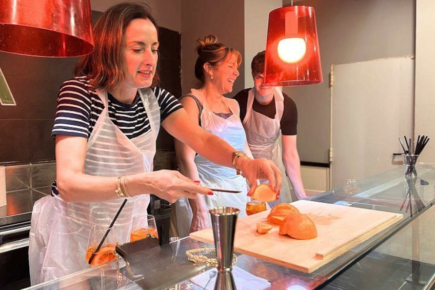 Tres personas en una cocina preparando comida, con una tabla de cortar y un cuchillo sobre la encimera. 5