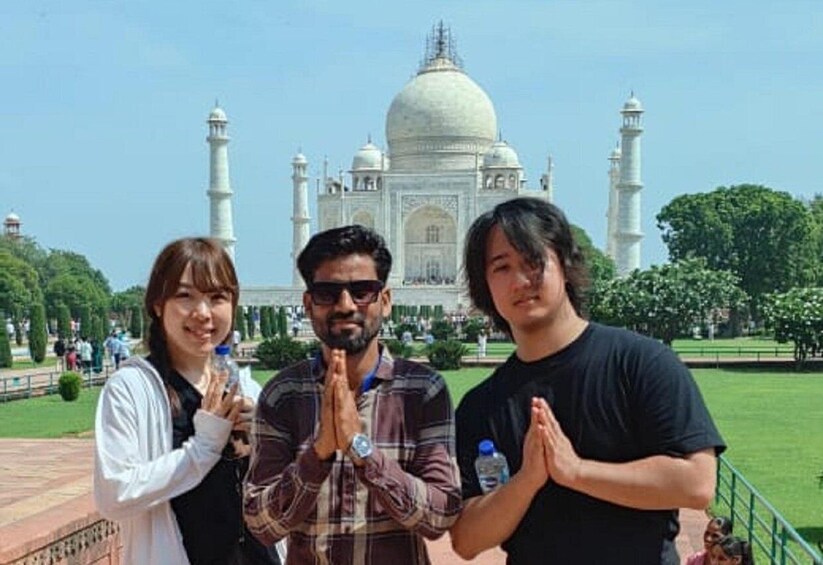 Three people in front of the Taj Mahal with the monument in the background. 4