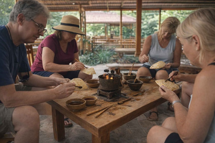 A group of people sitting around a wooden table with a fire, cooking food. 3