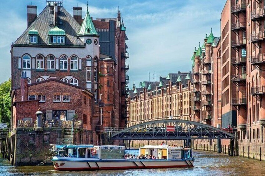 A boat on a canal, a bridge, and historic buildings with red brick facades. 5