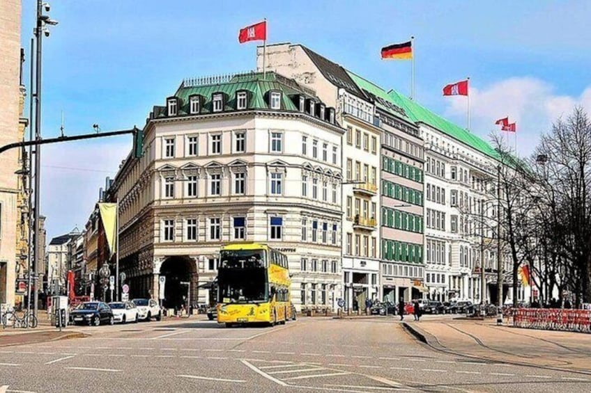 A street with a yellow bus, a large building with multiple flags, and a tram line. 2