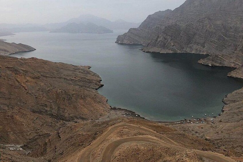 A mountainous landscape with a large body of water, a winding dirt road, and a rocky terrain. 2