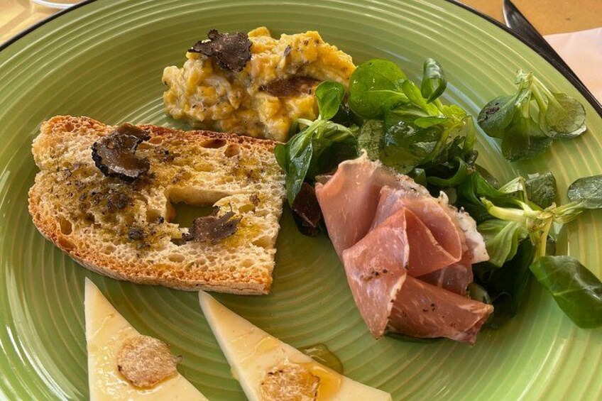 Une assiette avec une tranche de pain garnie de champignons, un morceau de fromage, une tranche de jambon et une petite salade. 4
