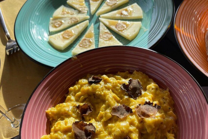 Une table avec trois plats : une assiette de fromage en tranches, un bol de risotto aux champignons et une assiette qui semble contenir un plat de viande. 3