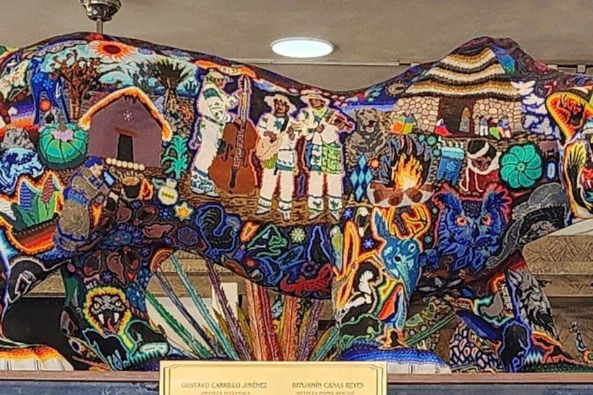 A colorful tapestry with intricate designs and figures, including a horse and a person playing a guitar. 4