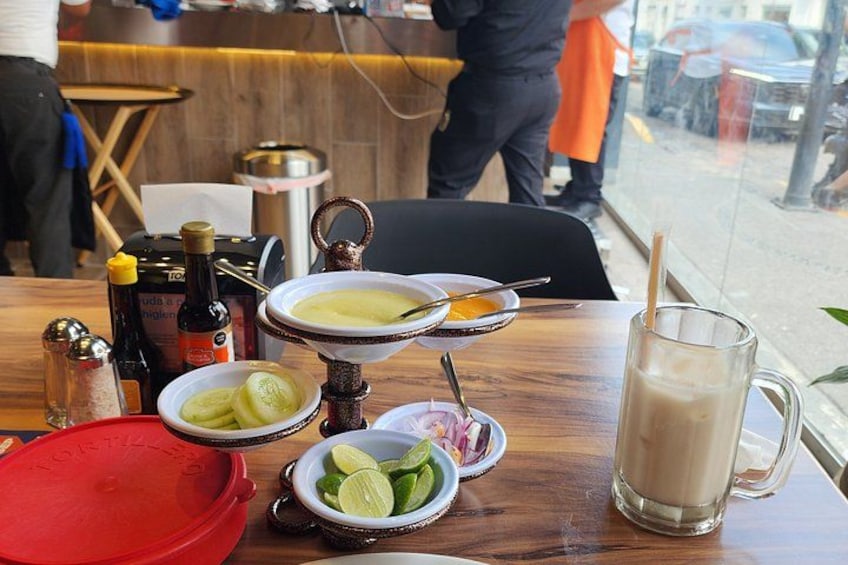 A table with a red bowl, a glass mug, and a plate with sliced cucumbers. 3