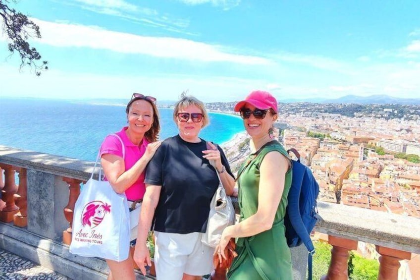 Tre persone su un balcone con vista su una città costiera. 2