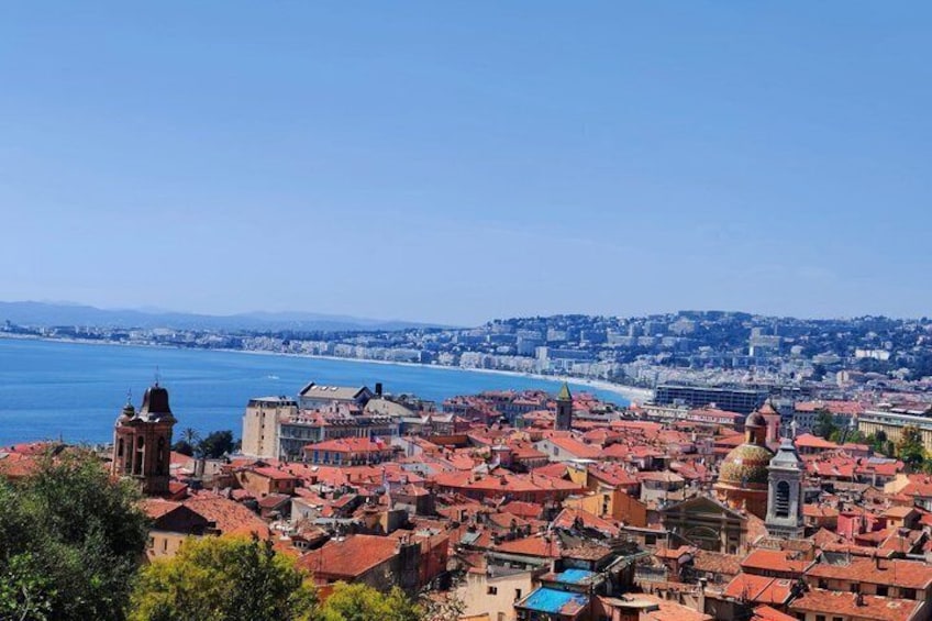 Paesaggio costiero con edifici dai tetti rossi, un'imponente torre e un mare blu e limpido. 5