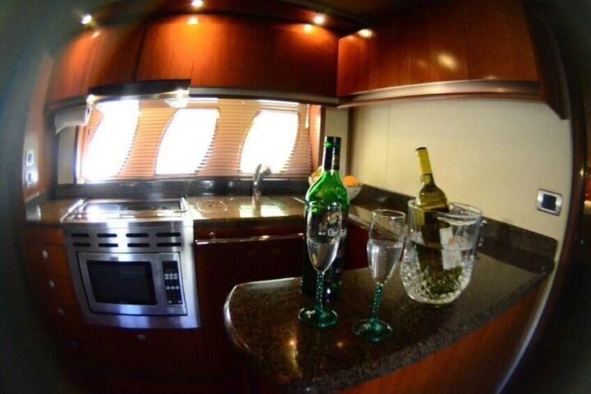 A compact kitchen with a microwave, a green bottle, and two glasses on the counter. 5