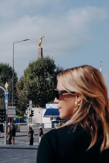 A statue on a pedestal, traffic lights, and a street sign. 5