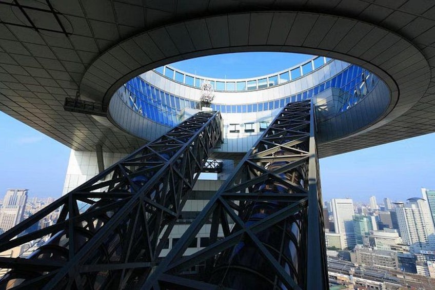 A spiral staircase leading to a circular observation deck with a cityscape in the background. 5