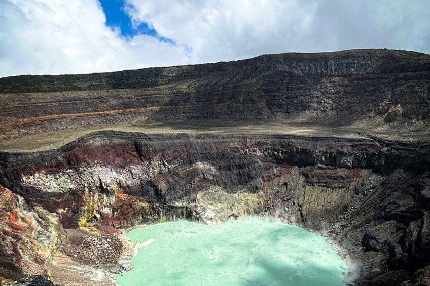A large crater with a turquoise pool at its center, surrounded by rugged terrain. 4