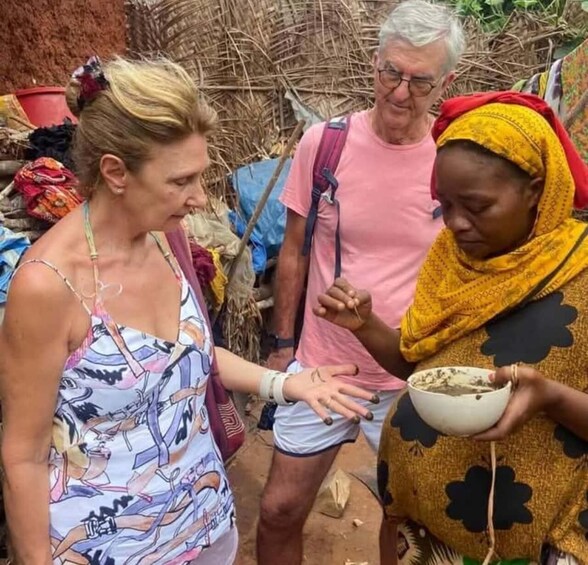 A group of people outdoors, one holding a bowl. 1