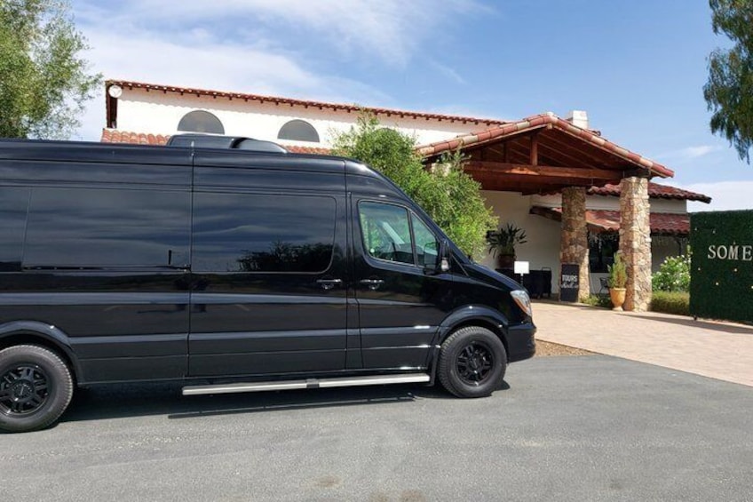 A black van parked in front of a building with a red roof and columns. 2