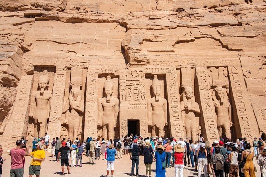 A large group of people gathered in front of a massive ancient Egyptian temple with towering statues. 2