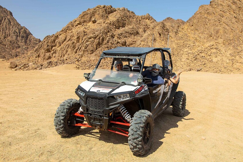A 4x4 off-road vehicle in a desert with rocky terrain and mountains in the background. 2