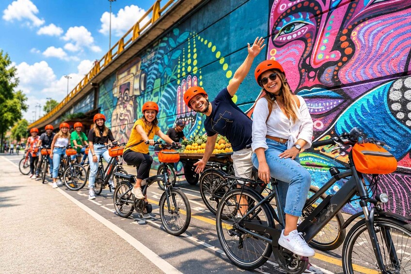 A group of people on bicycles, some wearing helmets, along a road with a colorful mural on the side. 1