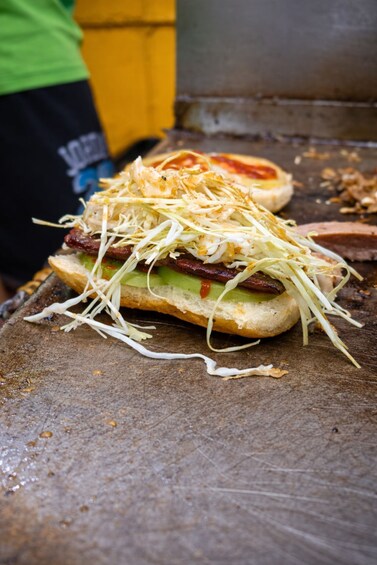 A sandwich with various toppings on a wooden surface. 1