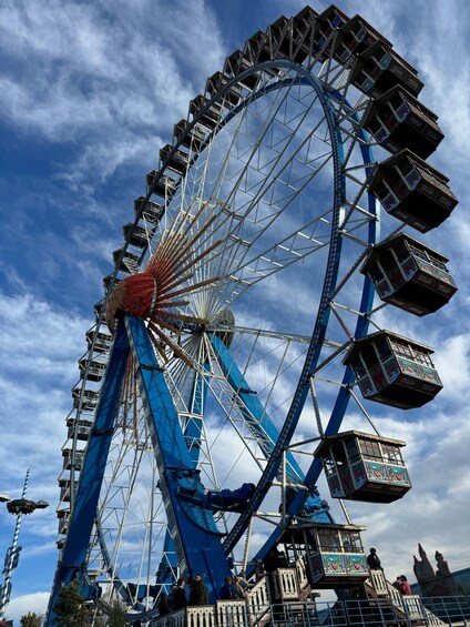 A large Ferris wheel with cabins, set against a partly cloudy sky. 5