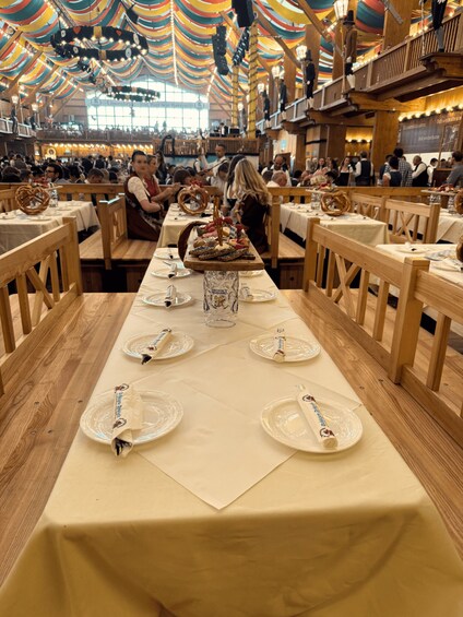 A restaurant with wooden tables, white tablecloths, and a festive atmosphere with colorful drapes. 2