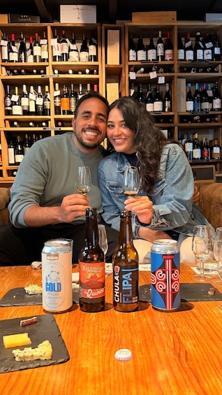 A couple holding wine glasses in a bar with shelves of wine bottles. 2