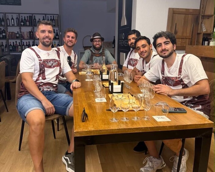 A group of people seated at a wooden table with wine glasses and bottles. 2