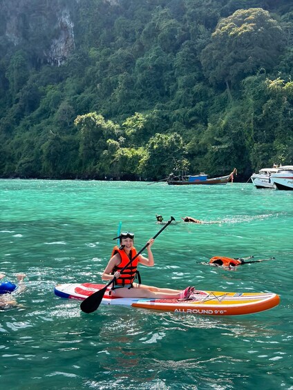 A person kayaking on turquoise water with a forested island in the background. 5