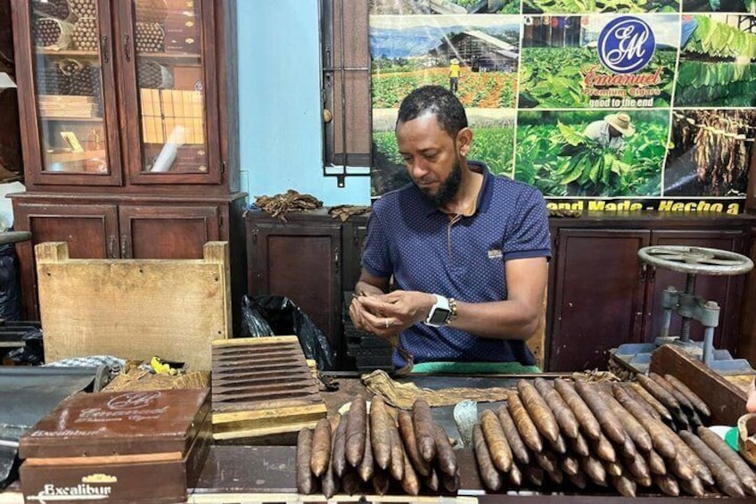 A man at a wooden counter with various items, including chocolate and what appears to be dried goods. 1