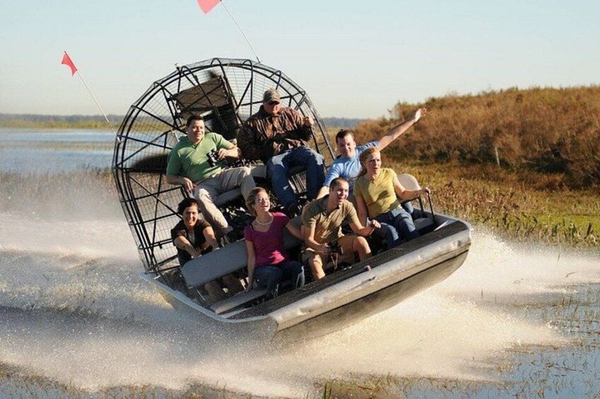 A group of people on a boat with a cage-like structure on top, moving through a body of water. 1