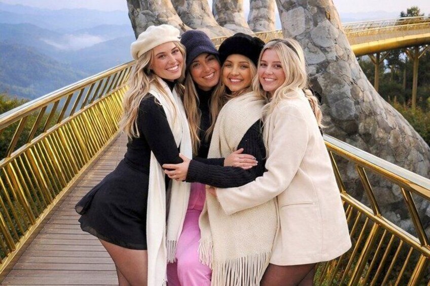 A group of people on a wooden bridge with stone pillars, surrounded by a mountainous landscape. 3