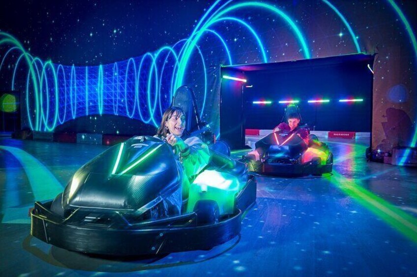 Zwei Personen fahren mit Autoscootern in einem Indoor-Freizeitpark mit Neonlichtern. 4