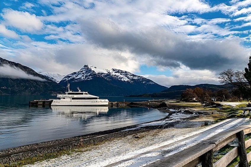 A boat docked at a pier with mountains in the background. 2