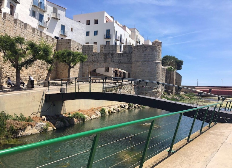 Un pont de pierre enjambe un canal, avec un mur de pierre et des bâtiments blancs en arrière-plan. 3