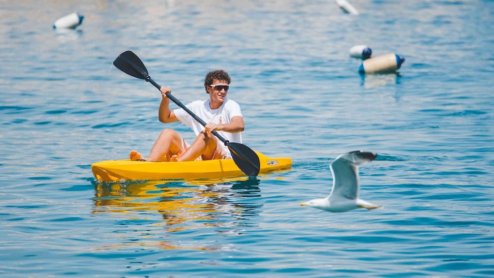 A person kayaking on a yellow kayak in calm water. 1