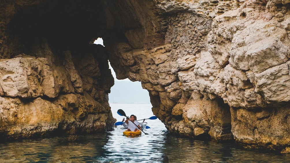 A kayaker in a cave opening with water. 5