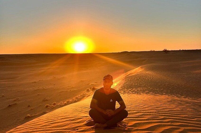 A person sitting on a sand dune at sunset. 1