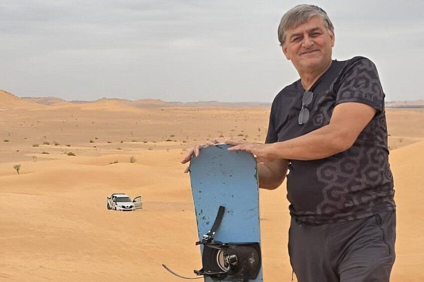 A person holding a blue object with a white vehicle in a desert landscape. 2