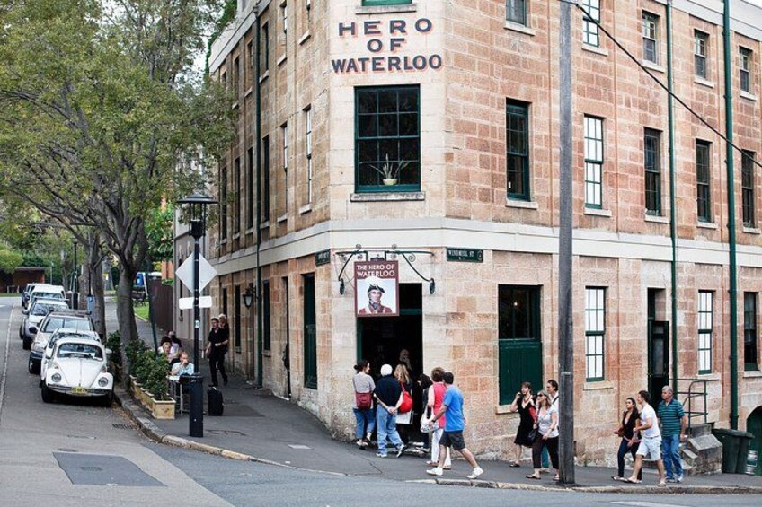 Un edificio con un letrero que dice 'Hero of Waterloo' y personas caminando por la acera. 2