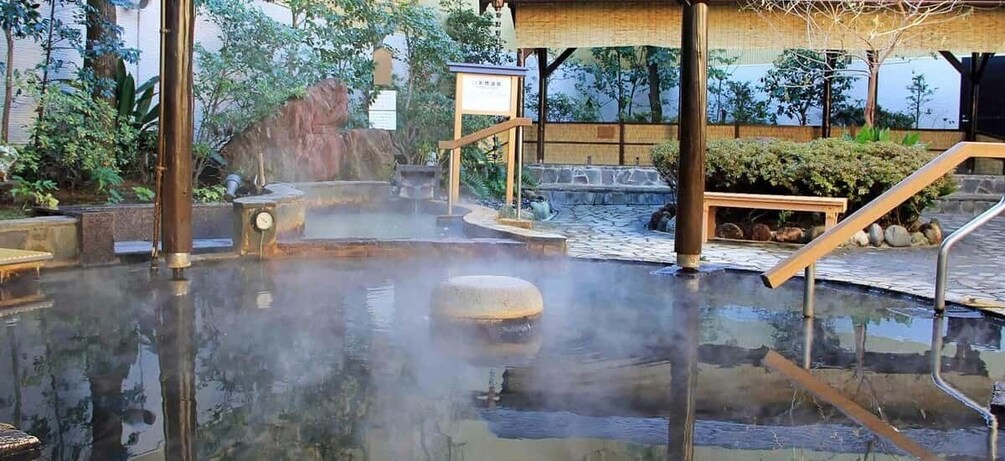 A hot spring bath area with stone steps, wooden railings, and a bamboo structure. 2