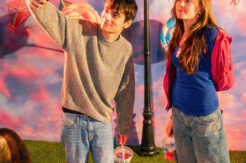 Two people standing on grass with a colorful sky in the background. 3