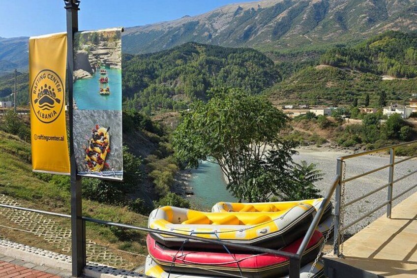 A river with a yellow raft, a flag, and a mountainous landscape. 2
