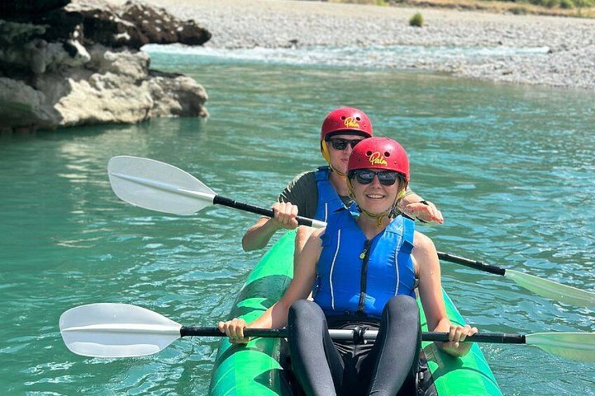 Two people kayaking on a calm river with rocks in the background. 5