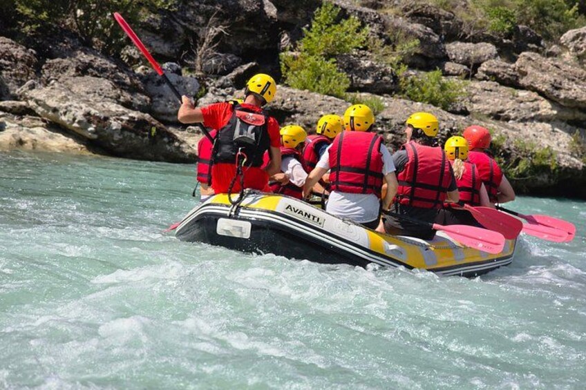 A group of people in a yellow and black inflatable raft on a river. 1