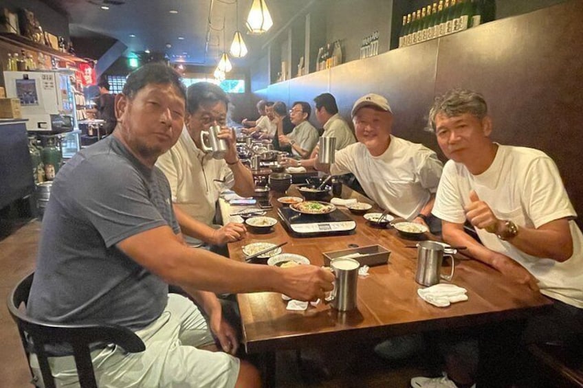 A group of people dining at a restaurant with wooden tables and chairs. 2