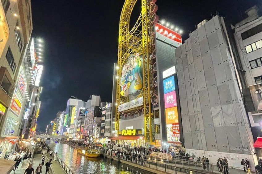 A busy urban street at night with illuminated billboards and a large Ferris wheel. 4