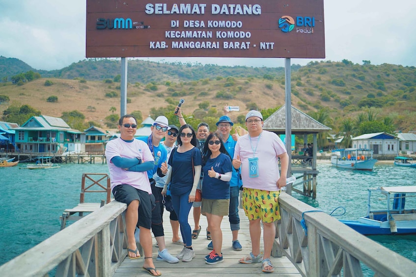 A group of people on a wooden pier with a signboard in the background. 5
