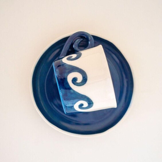 A ceramic mug with a white and blue swirl design on a blue plate. 4