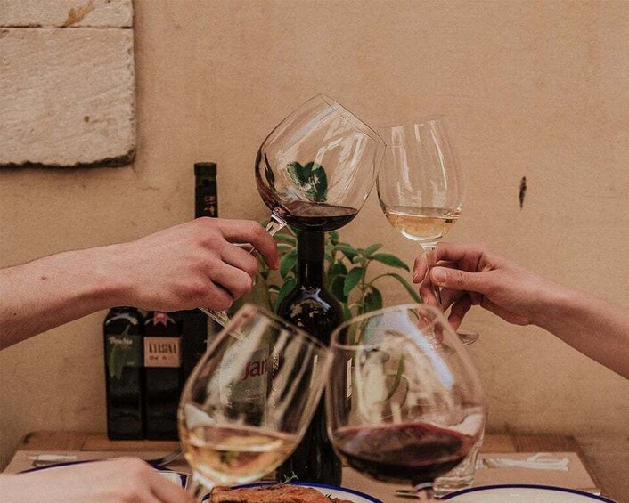 Two people toasting with wine glasses, a bottle of wine, and a plant in the background. 2