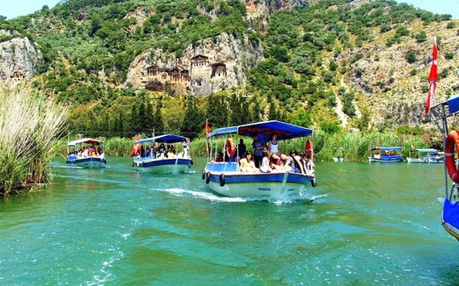 A group of boats on a river with passengers, surrounded by lush greenery and rocky cliffs. 4