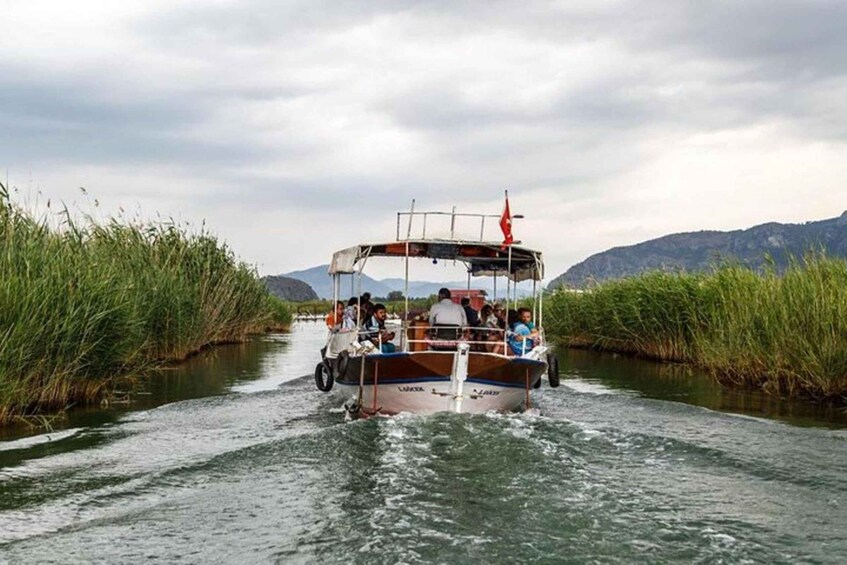 A boat with passengers traveling through a narrow waterway flanked by tall grass. 1